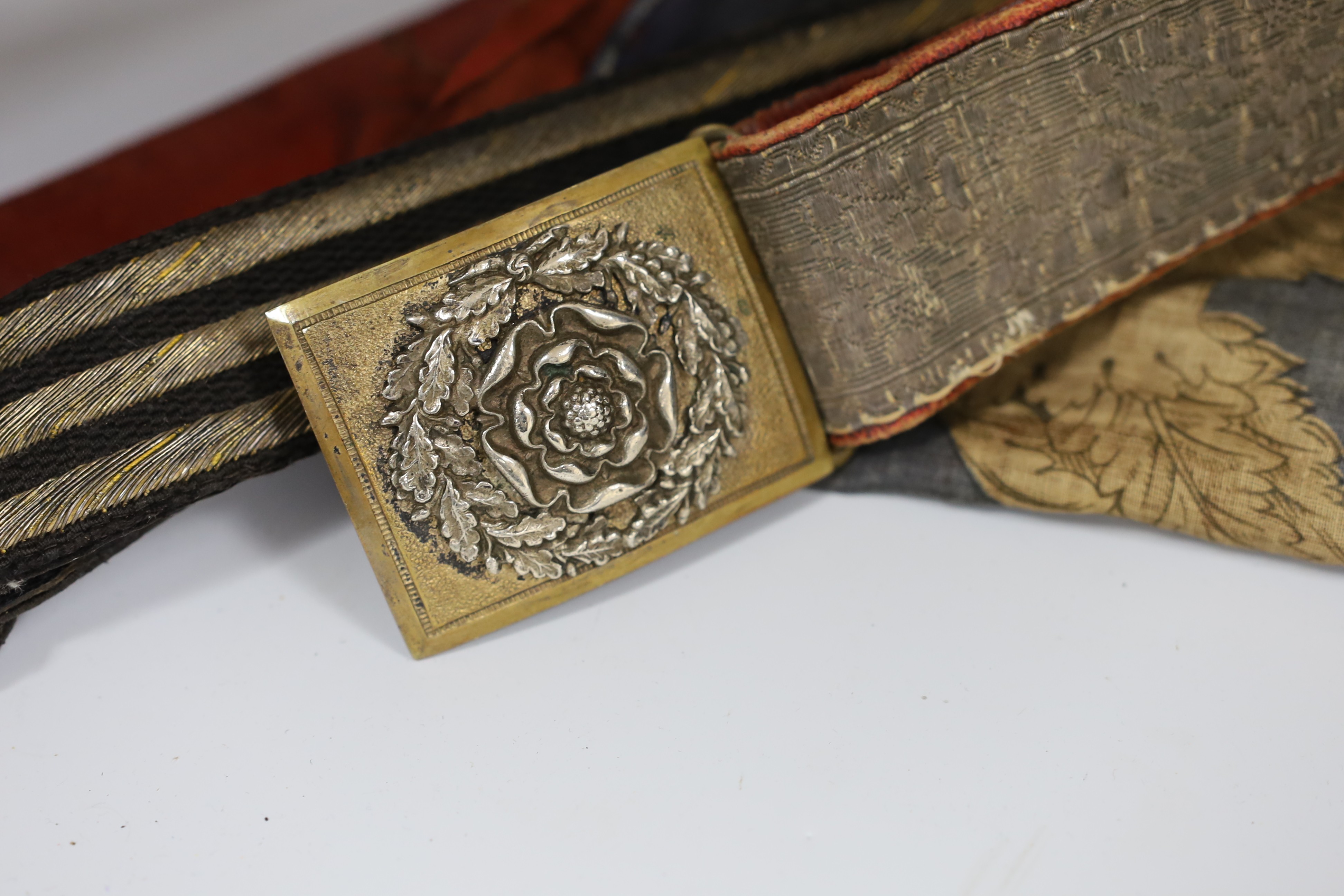 A Royal Naval gilt brass mounted officers belt, an Edwardian Dieu et mon droit belt, a Victorian printed flag and A Victorian Yorkshire Regiment officers brocade sword belt